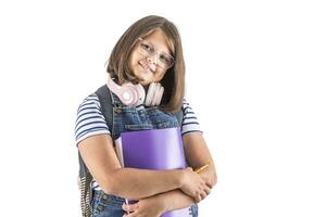 School attending girl in glasses and headphones on her neck smiles as she holds exercise books photo