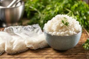 Cooked rice in a bowl with raw rice in plastick bags. photo