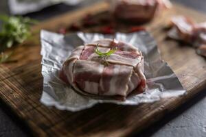 Detail of a cheese and bacon wrap ready for frying, placed on a cutting board photo