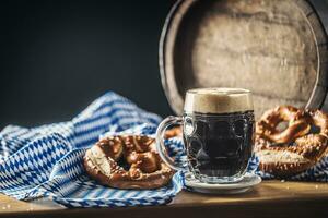 Oktoberfest oscuro cerveza con galleta salada de madera barril y azul Manteles foto