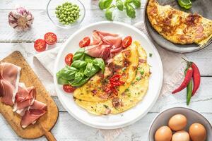 tortilla con jamón chícharos albahaca Tomates y hierbas en blanco plato foto