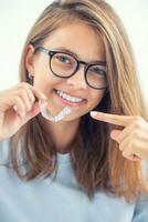 Dental invisible braces or silicone trainer in the hands of a young smiling girl. Orthodontic concept - Invisalign photo