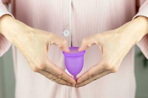 Close-up of a woman's hands holding a silicone menstrual cup. Alternative ecological feminine hygiene product during menstruation waste-free concept photo