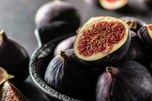 A few figs in a black bowl on an dark concrete table photo