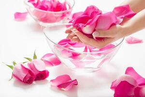 Female hands and bowl of spa water with pink roses and  petals photo