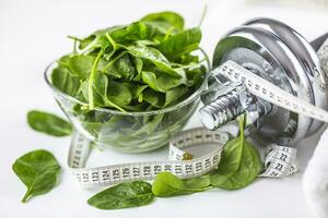 Spinach dumbbells and measure tape isolated on white background photo