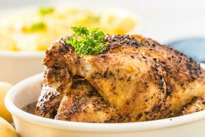 Whole chicken roasted in a porcelain bowl with potatoes photo