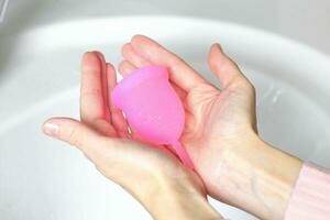 Close-up of a woman holding a silicone menstrual cup. Alternative ecological feminine hygiene product during menstruation waste-free concept photo