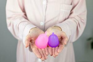 Close-up of a woman's hands holding a silicone menstrual cup. Alternative ecological feminine hygiene product during menstruation waste-free concept photo