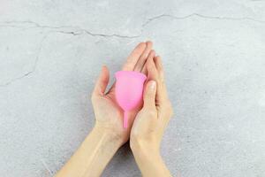 Close-up of a woman's hands holding a silicone menstrual cup. Alternative ecological feminine hygiene product during menstruation waste-free concept photo