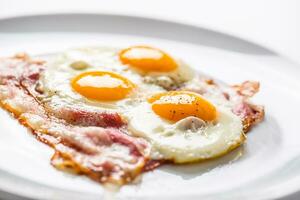 Ham and Eggs. Bacon and Eggs. Salted egg with pepper on white plate. English breakfast photo