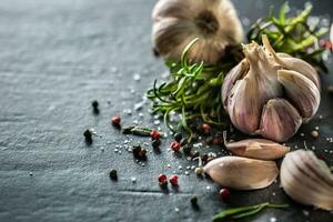 Garlic cloves and bulb with fresh rosemary salt and spice on concrete table photo