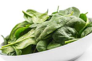 Spinach. Fresh baby spinach leaves in plate isolated on white photo