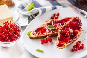 sabroso desayuno con rojo grosellas mermelada croissants mantequilla y menta hojas foto