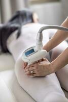 mujer acostado en un productos cosméticos estudio mesa obtiene glp endermologie tratamiento de su piernas por un electrónico dispositivo foto