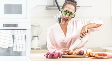 Female protects herself from onion cutting smell by a snorchel while standing in the kitchen dressed in silk nightgown photo