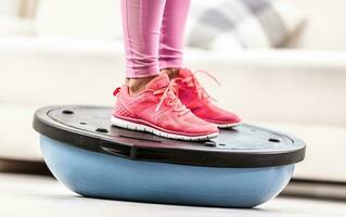 Woman in training shoes stands on a blue balance ball photo