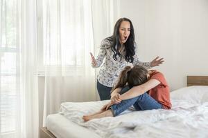 Abusive mother shouts at her daughter at home while the girl tries to hide her head between her legs photo