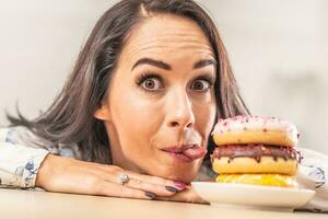 Girl trying to at least lick a pile of donuts on a plate in front of her photo