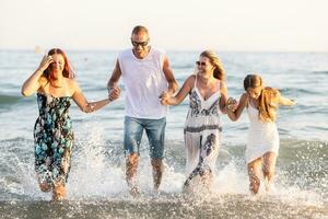 The complete family runs hand in hand from the beach to the sea, enjoying a joint vacation by the sea photo