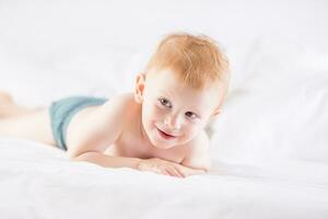 Habby young smilling child boy in white bed photo