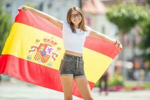 contento niña turista caminando en el calle con Español bandera foto