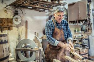 Old-fashioned way of processing wood as aged carpenter holds tools to smooth the wooden surface photo