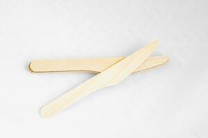 Disposable eco friendly wooden knifes on white background. Eco friendly disposable wooden cutlery on white background. photo