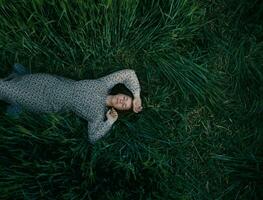 Young girl lying on green wheat field photo