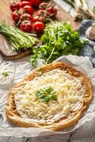 Precisely prepared hungarian traditional langos with lovely crust greased with garlic, cream, cheese and herbs, served with vegetables in the backround photo