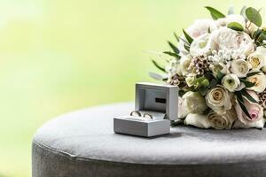 Open box with wedding rings placed next to a bouquette during a wedding photo