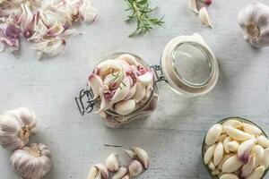 Top view jar full of garlic cloves, a bowl full of lovely peeled garlic cloves and savory rosemary photo