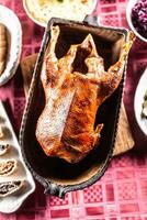 Crispy baked goose in an original baking dish on the festive table - Top of view photo