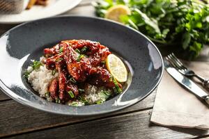 Asian style honey glazed chicken, coriander leaves, rice and lemon photo