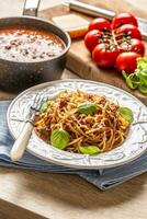 Italian pasta spaghetti bolognese served on white plate with parmesan cheese and basil photo