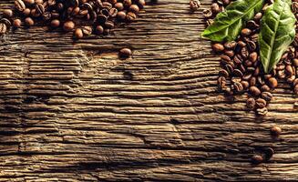 Top of view coffee beans and green leaves on rustic oak table photo