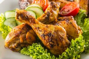 Roasted chicken legs with lettuce salad and tomatoes photo