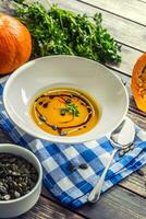 Pumpkin cream soup with seeds and parsley on kitchen table photo