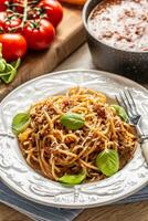 Italian pasta spaghetti bolognese served on white plate with parmesan cheese and basil photo