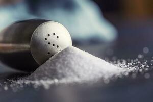 Spilled salt with staniless salt shaker - Closeup photo