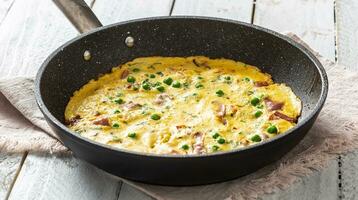 Omelette with prosciutto peas and herbs in ceramic pan on table photo