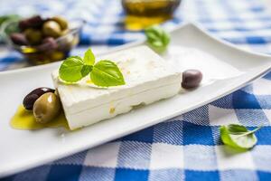 Greek cheese feta with olive oil olives and basil leaves photo
