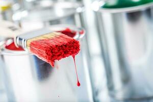 Close-up brush with red color lying on paint can. photo