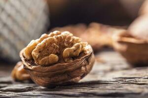 Close-up walnut kernel and whole walnuts on old wooden table photo