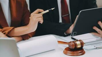 Business and lawyers discussing contract papers with brass scale on desk in office. Law, legal services, advice, justice and law concept picture with film grain effect video