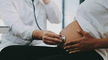 contento embarazada mujer visitar ginecólogo médico a hospital o médico clínica para el embarazo consultor. médico examinar embarazada barriga para bebé y madre cuidado de la salud cheque arriba. ginecología concepto. video