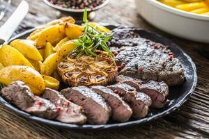 Grilled beef Rib Eye steak with garlic american potatoes rosemary salt and spices photo