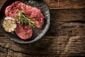 Beef meeat Rib-Eye steak wit rosemary salt and pepper on black plate photo