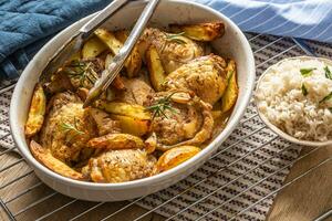 Chicken legs roasted with american potatoes in baking dish photo