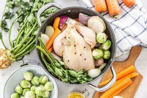 Chicken ready to cook broth with fresh root vegetables and spices photo